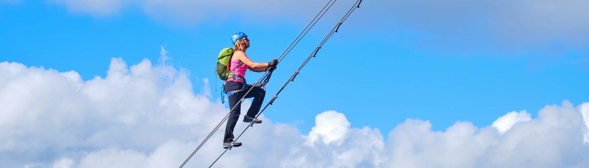 A woman climbing up the spectacular sky ladder of the via ferrata for the brave at Donnerkogel under the instruction of the experienced guides from Bergführer Salzburg.