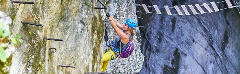 A woman climbing up the steep "Gamsleckenwand" on her Via Ferrata Tour for Adventurers at Postalm with the experienced guides from Bergführer Salzburg.
