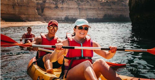 Tour en Kayak desde la Praia de São Rafael a sus cuevas y acantilados con Albufeira Surf & SUP Personas en un kayak durante su recorrido en kayak desde Praia do Castelo hasta las Cuevas y Acantilados con Albufeira Surf & SUP.