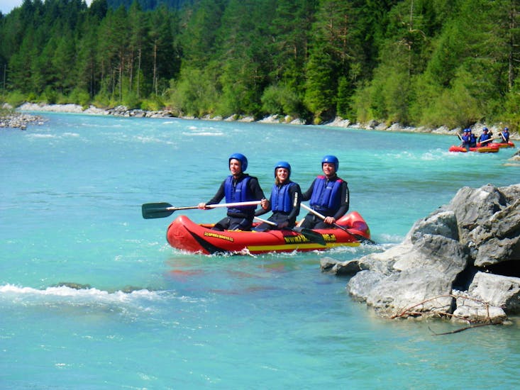 Drei Freunde paddeln bei ihrem Kanadier-Rafting auf dem Lech - Halbtagestour mit Fun Rafting Lechtal den türkisfarbenen Fluss Lech hinunter.