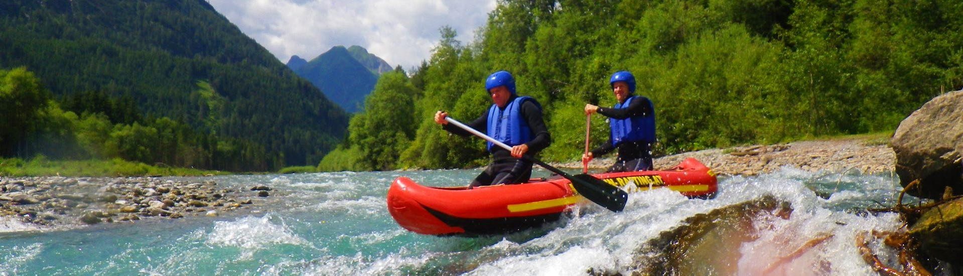 Two participants of the Canoe Rafting on the Lech River - Full Day Tour with BBQ organized by Fun Rafting Lechtal are mastering a rapid on the river in their inflatable canoe.