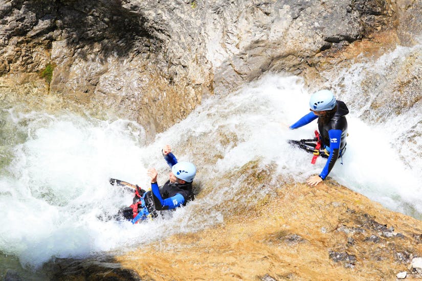 Die Teilnehmer des Fun Canyoning in der Wiesbachschlucht mit Fun Rafting Lechtal rutschen über eine natürliche Wasserrutsche in der Schlucht.