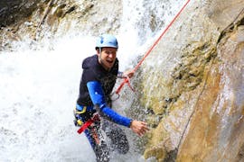 A participant of the Canyoning in the Hochalpschlucht with Fun Rafting Lechtal is roping down a thundering waterfall in the canyon.