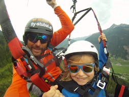 A pilot and a child while Tandem Paragliding in Stubaital for Kids (3-15 y.) with FlyStubai.
