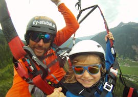 A pilot and a child while Tandem Paragliding in Stubaital for Kids (3-15 y.) with FlyStubai.