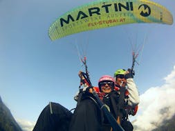 Ein Mädchen fliegt mit ihrem Tandempiloten von Fly-Stubai während dem Tandem Paragliding im Stubaital - Morgenflug über die Berge und genießt dabei die atemberaubende Aussicht.