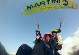 A girl is flying with her tandem pilot from Fly-Stubai during the morning tandem paragliding in Stubaital over the mountains and enjoying the breathtaking view.