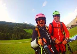 After the landing of the tandem paragliding in Stubaital - thermic flight, the girl looks excitedly into the camera and takes a photo with her GoPro and her tandem pilot from Fly-Stubai.