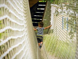 Un niño pequeño camina a lo largo de una red durante el parque de aventuras - Ruta Mini Pitchoun, con Accroche toi aux branches.