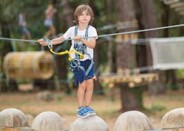 Ein Kind läuft auf Blöcken im Abenteuerpark - Maxi Pitchoun, Aktivität mit Accroche toi aux branches.