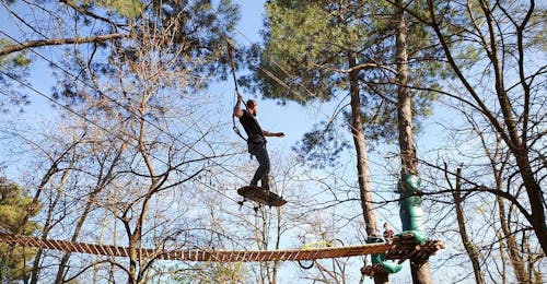 Parco Avventura in Ardèche - Percorso Sportivo con Accroche toi aux branches Ardèche Una bambina cammina lungo una rete durante il "Percorso Sportivo" con Accroche-toi aux branches.