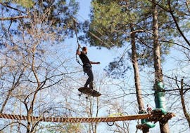 Ein Mann in der Luft während eines Hindernisses des Adventure Park - Sportaktivität von Accroche toi aux branches.