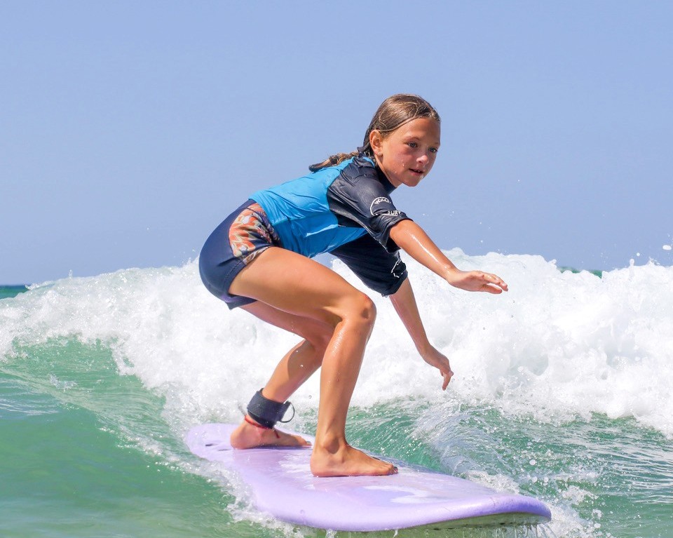 Een meisje berijdt een golf dankzij haar surflessen voor kinderen (6-11 jaar) op Culs Nus Beach met Hossegor Surf Center.