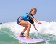 Una niña monta una ola gracias a sus Clases de surf para niños (6-11 años) en la playa de Culs Nus con Hossegor Surf Center.