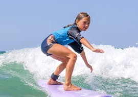 Une fillette surfe sur une vague grâce à son Cours de surf Enfants (6-11 ans) sur la plage des Culs Nus avec Hossegor Surf Center.
