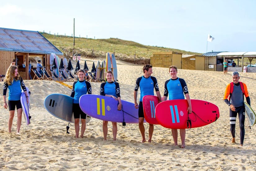 Un groupe de surfeurs se dirige vers l'eau avec leur planche sous les bras pour leurs Cours de surf - Plage des Culs Nus - Tous niveaux avec Hossegor Surf Center.