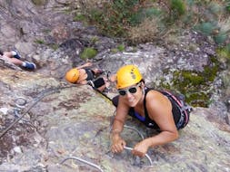 Una mujer está escalando un acantilado durante su actividad de vía ferrata en Ardèche - Pont du Diable, con Les Intraterrestres.
