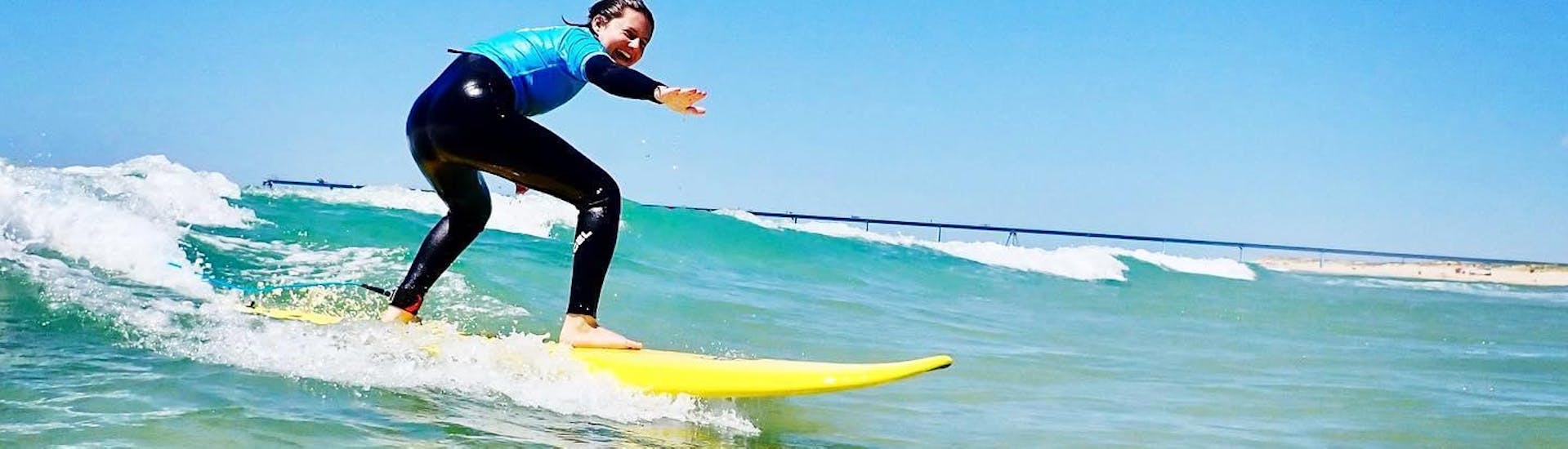 A girl is surfing during the private Surfing Lessons on Salie Beach for All Levels with Pyla surf school.
