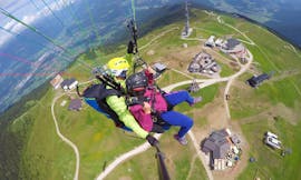 A young woman is gliding over the peak of Plan de Corones with her tandem pilot during the Tandem Paragliding from Plan de Corones with Tandemflights Kronplatz.