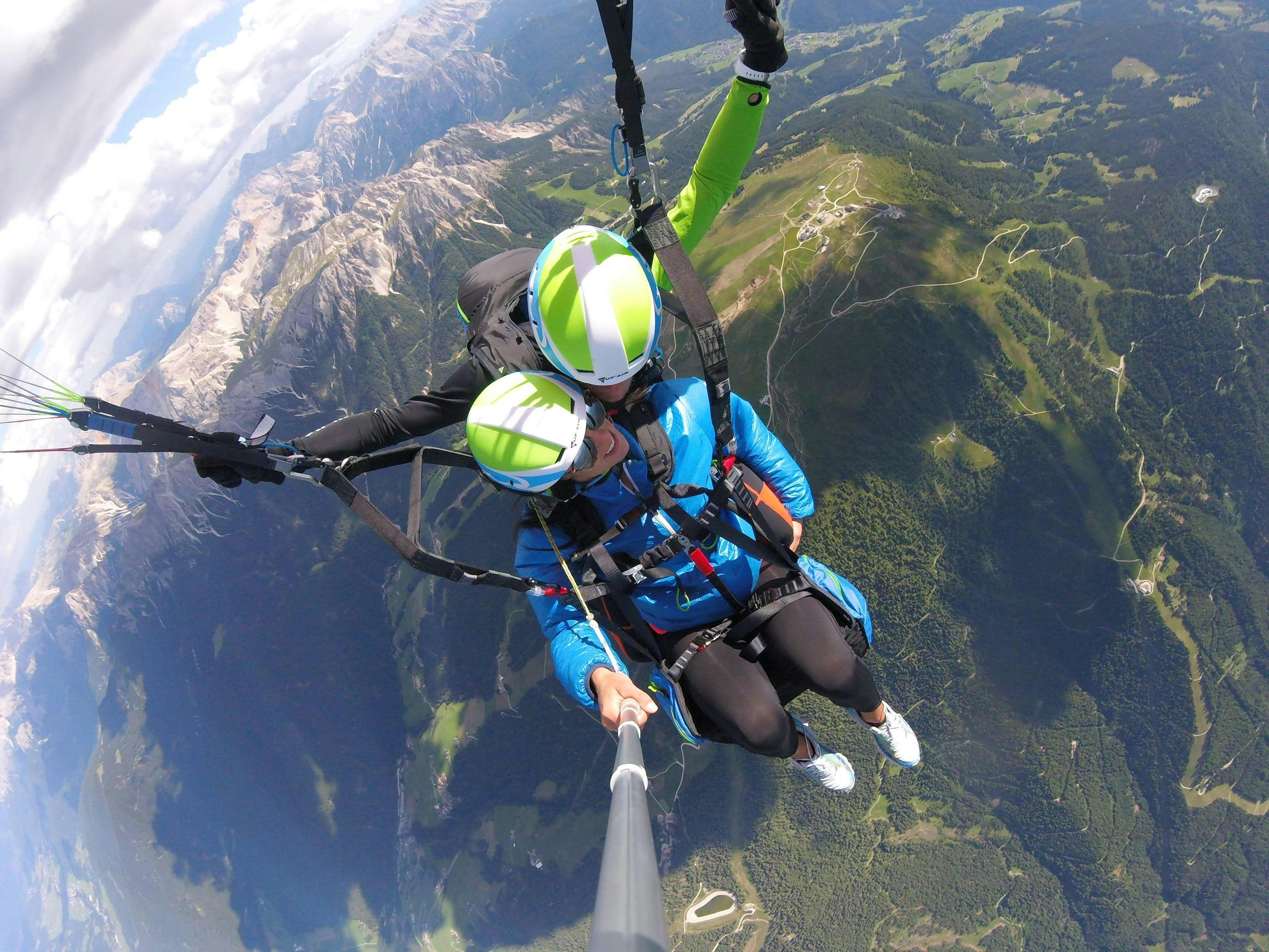 A tandem pilot from Tandemflights Kronplatz and his passenger are enjoying the view of the Puster Valley during the Thermic Tandem Paragliding from Plan de Corones.