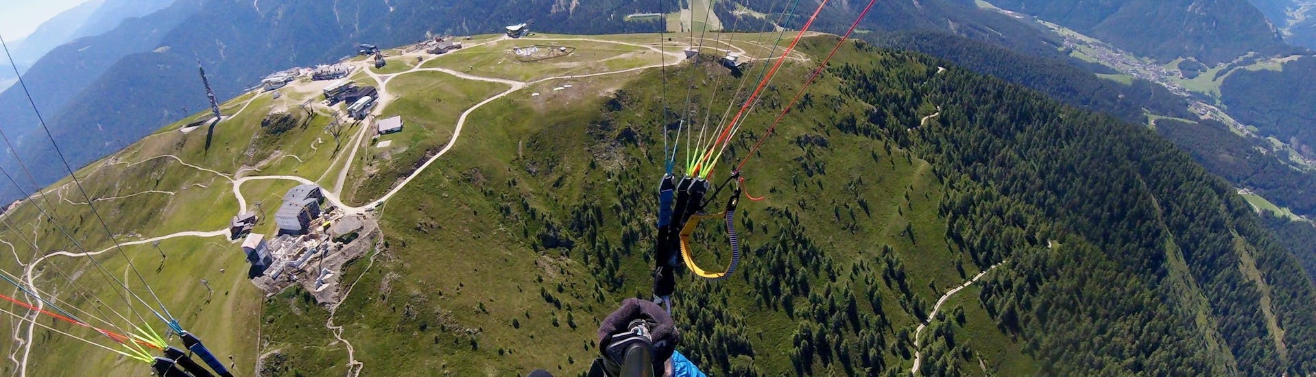 A tandem pilot from Tandemflights Kronplatz and his passenger are enjoying the view of the Puster Valley during the Thermic Tandem Paragliding from Plan de Corones.
