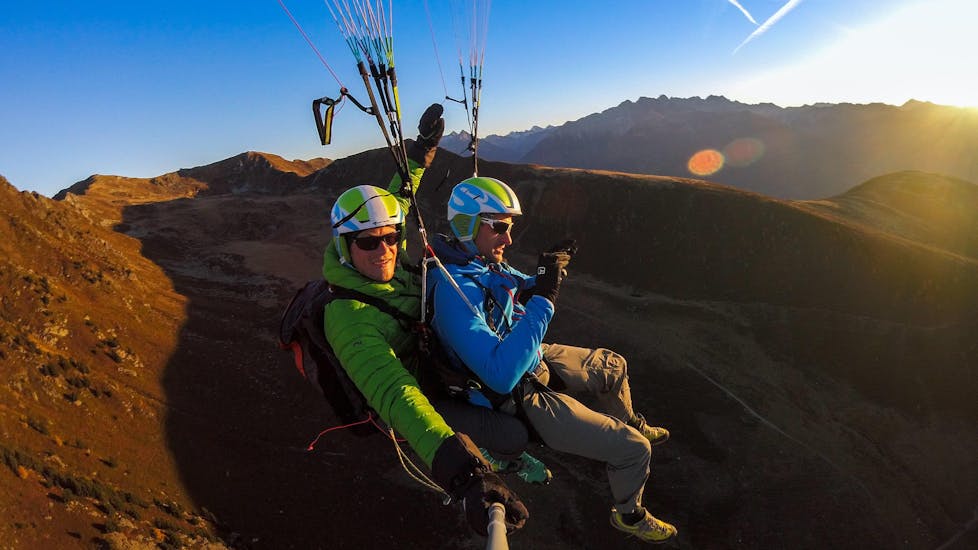 Während des Tandem Paragliding vom Speikboden bei Sonnenaufgang genießen ein Tandempilot und sein Passagier den ruhigen Flug am frühen Morgen.