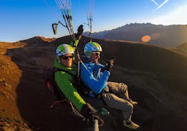 During the Tandem Paragliding from Monte Spico at Sunrise, a tandem pilot and his passenger are enjoying the calm flight in the early morning.