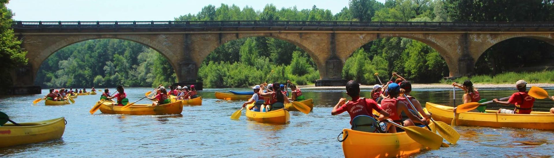Holidaymakers are paddling on the Dordogne River during their 9 km canoe trip with Canoës Loisirs Dordogne.