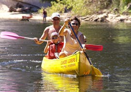 A couple and their child are paddling on the Dordogne River during their 9 km canoe trip with Canoës Loisirs Dordogne.