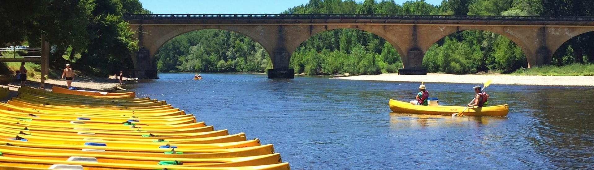 Holidaymakers are paddling on the Dordogne River during their 19 km canoe trip with Canoës Loisirs Dordogne.