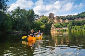 Des vacanciers pagayent sur la Dordogne devant le château de Beynac pendant leur sortie en canoë de 25 km avec Canoës Loisirs Dordogne.