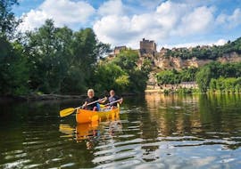Holidaymakers are paddling on the Dordogne River in front of the Beynac Castle during their 25 km canoe trip with Canoës Loisirs Dordogne.