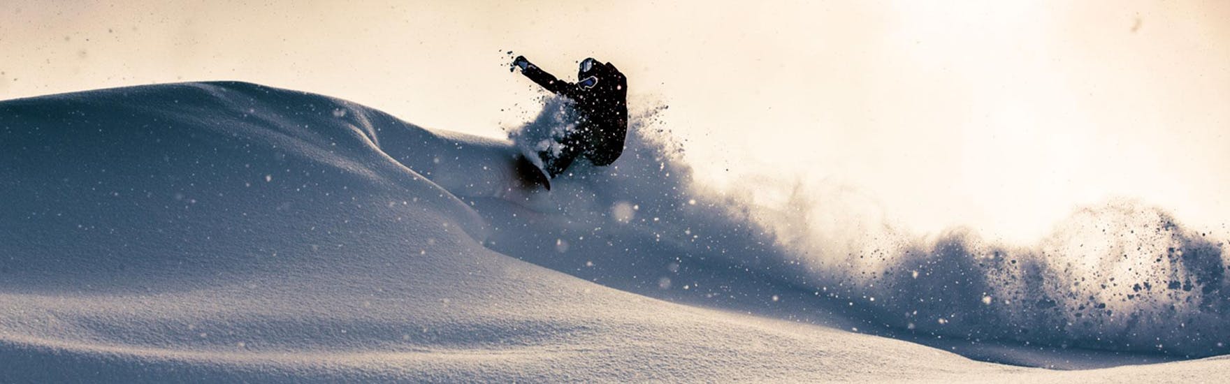 A snowboarder is riding through deep powder snow during his Off-Piste Snowboarding Lessons - All Levels with BOARD.AT.
