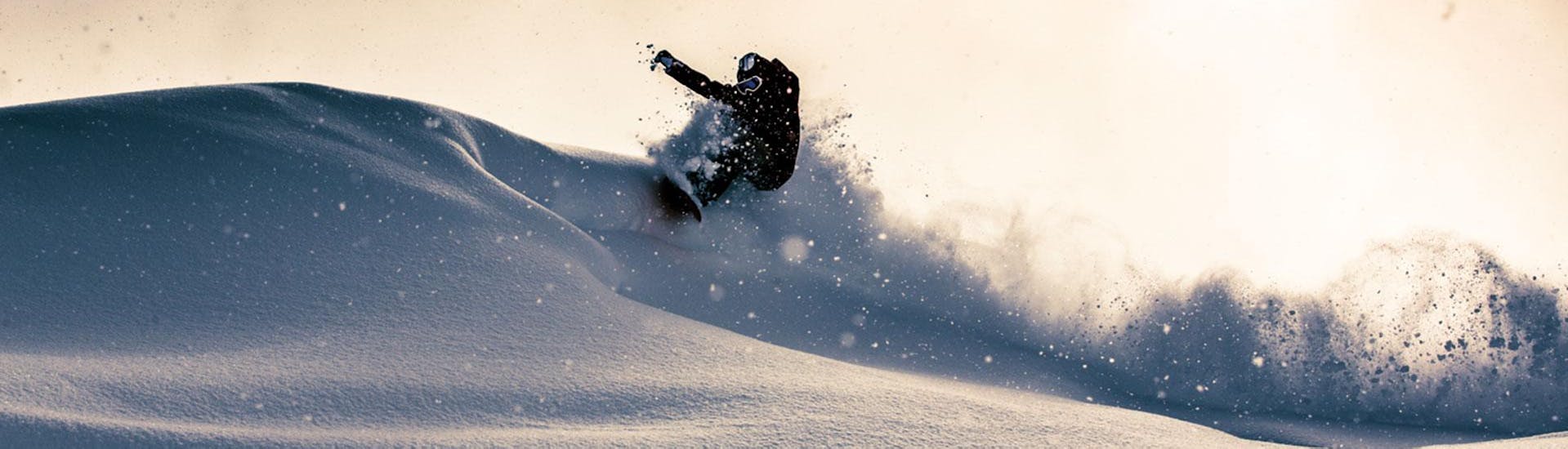 A snowboarder is riding through deep powder snow during his Off-Piste Snowboarding Lessons "Package" - All Levels with BOARD.AT.