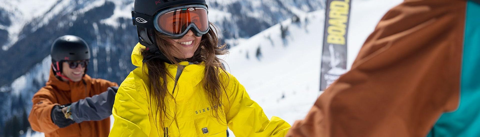 Een jonge vrouw wordt bijgestaan ​​door haar snowboardleraar van BOARD.AT tijdens haar privé-snowboardlessen voor kinderen en volwassenen - beginners.