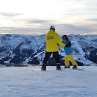 Der Snowboardlehrer steht gemeinsam mit seinem Kursteilnehmer am Berg und erklärt ihm die richtige Technik im Rahmen des Angebots "Privater Snowboardkurs für Kinder und Erwachsene - Anfänger" der Snowboardschule BOARD.AT.