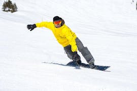 Ein Snowboarder fährt die sonnige Piste hinunter und genießt dabei den Neuschnee im Rahmen des Angebots "Privater Snowboardkurs - Fortgeschritten" der Snowboardschule BOARD.AT.