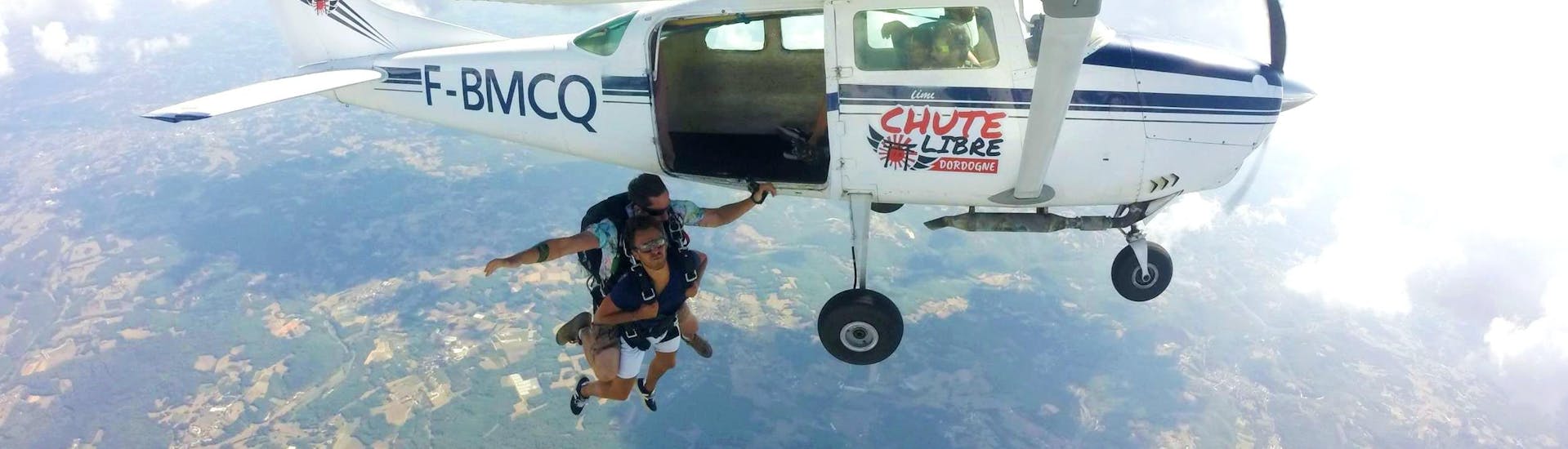 Un homme saute de l'avion avec son moniteur pour effectuer un saut en parachute tandem dans le Périgord avec Chute Libre Dordogne.