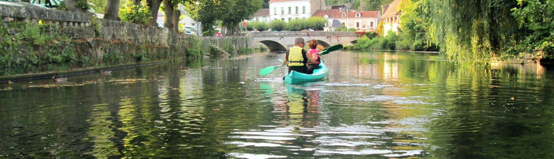 A couple is paddling on the Dronne river in the middle of the charming village of Brantome during their Moulin de Grenier - 4km canoeing tour with Allo Canoes Dordogne.