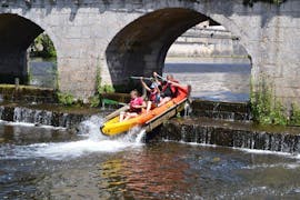 Eine Familie passiert eine Rutsche auf ihrem Kanu während ihres Tages mit dem Kanuverleih in Brantôme auf der Ganztagestour auf dem Fluss Dronne - 12 km.