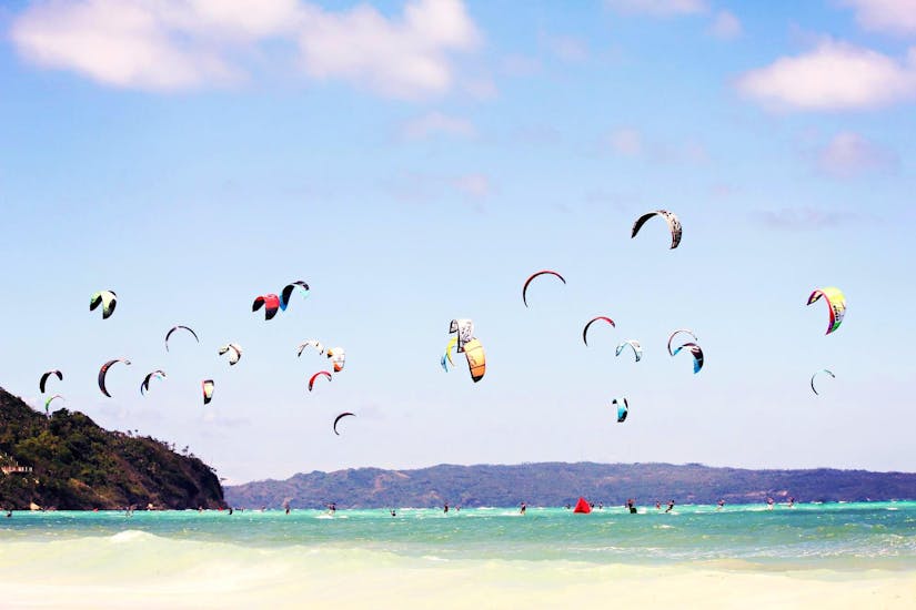 Un groupe de personnes surfant sur leur cerf-volant sur la plage pendant les leçons semi-privées de kitesurf en binôme pour les débutants avec Unikite Leucate.