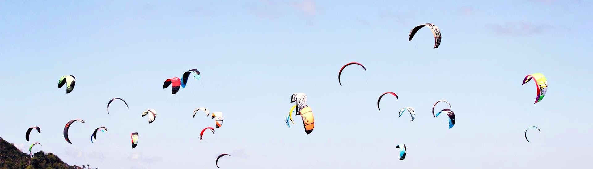 Un groupe de personnes surfant sur leur cerf-volant sur la plage pendant les leçons semi-privées de kitesurf en binôme pour les débutants avec Unikite Leucate.
