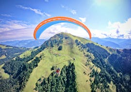 A tandem pilot from TirolAir and his passenger are gently floating over the peaks of the Kitzbühel Alps while paragliding from the Hohe Salve.