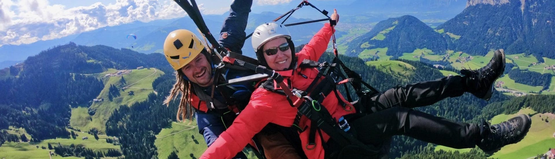 A tandem pilot from TirolAir and his passenger who has booked the Discovery Flight are seemingly enjoying themselves while paragliding from the Hohe Salve mountain.