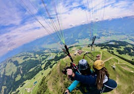 Ein Tandempilot und sein Passagier genießen beim Paragliding von der Hohen Salve die Aussicht auf das umliegende Bergpanorama.