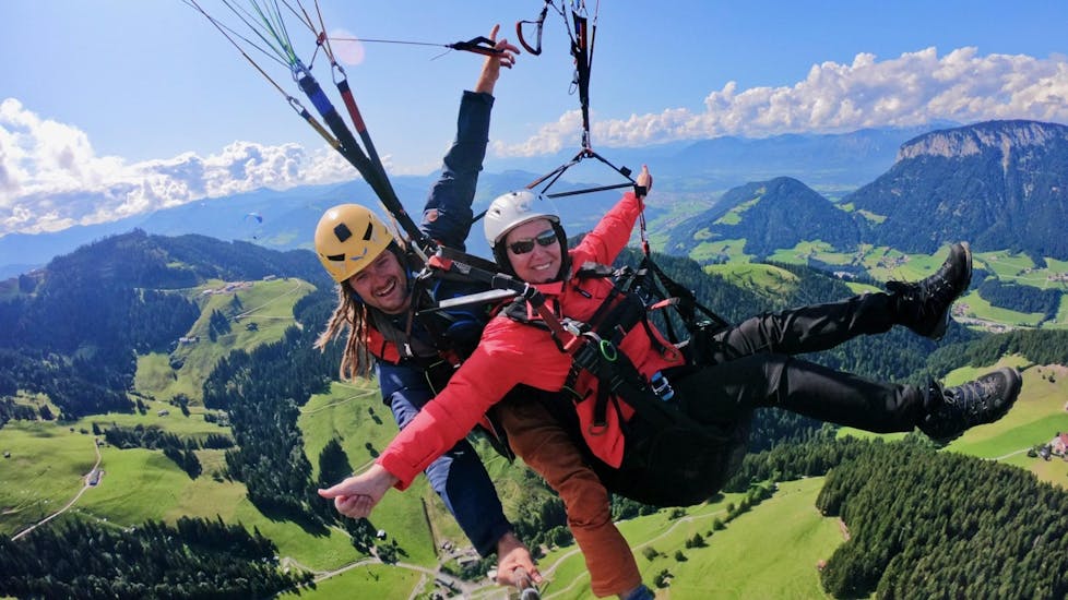 A tandem pilot from TirolAir and his passenger who has booked the Thermal Flight are seemingly enjoying themselves while paragliding from the Hohe Salve mountain.