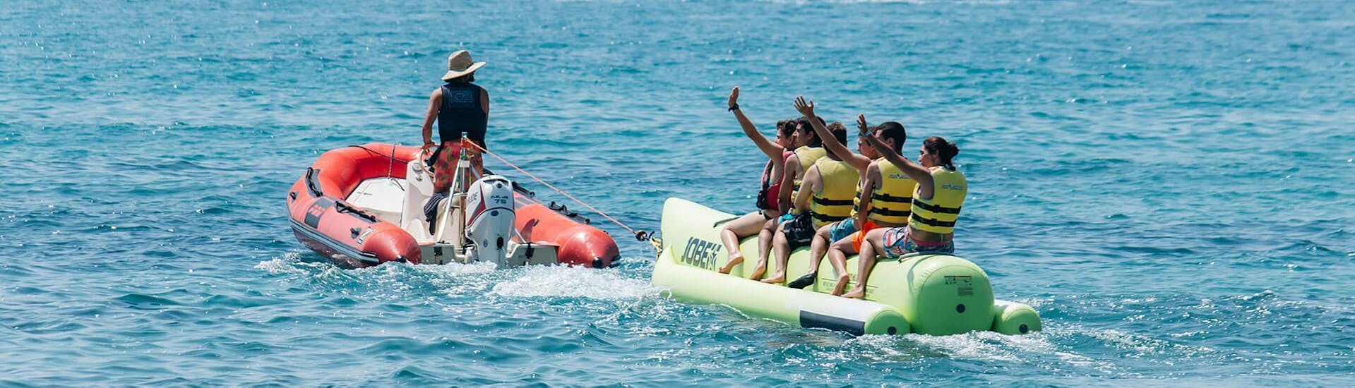 Eine Gruppe von Freunde lässt sich vom Boot durchs Meer ziehen während einer Tour mit dem Banana Boot in Salou organisiert von Estació Nàutica Costa Daurada.