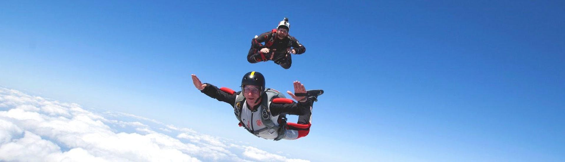 A man is enjoying his tandem skydive from 4000m above Saint-Ghislain to the fullest whilst being in good hands of a qualified tandem master from Skydive Saint-Ghislain.