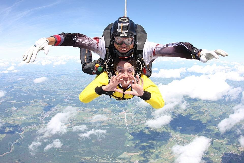 Une femme profite pleinement de son saut en tandem à 4 000 m au-dessus de Saint-Ghislain tout en étant entre les bonnes mains d'un pilote de tandem qualifié de Skydive Saint-Ghislain.