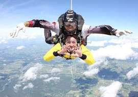 Une femme profite pleinement de son saut en tandem à 4 000 m au-dessus de Saint-Ghislain tout en étant entre les bonnes mains d'un pilote de tandem qualifié de Skydive Saint-Ghislain.